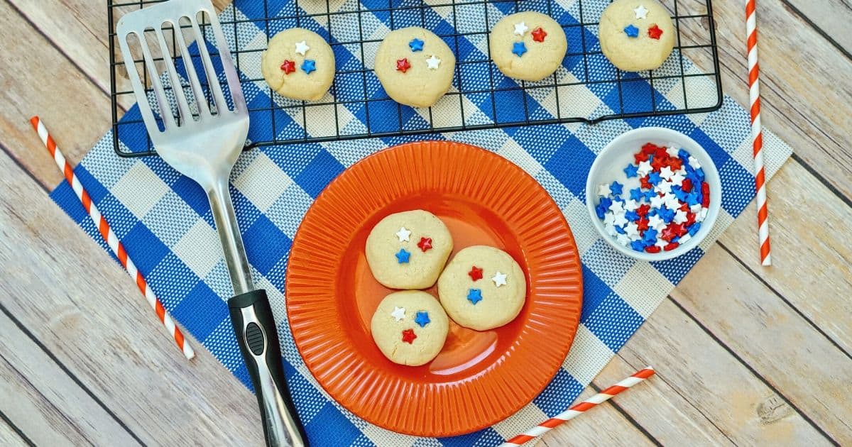 patriotic sugar cookies on red plate and baking rake with spatula and blue tablecloth