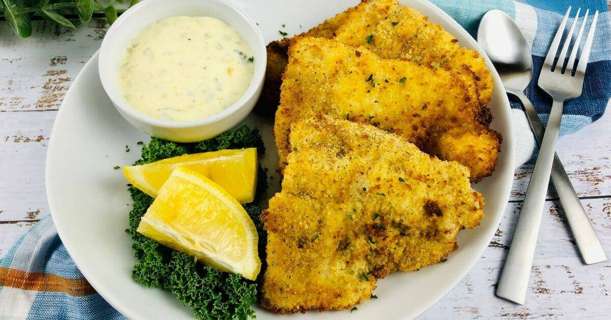 gluten free air fryer catfish on a plate with dipping sauce and lemon wedge