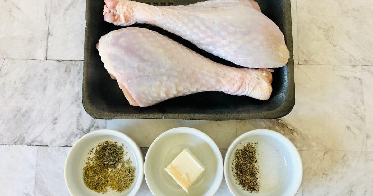 two raw air fryer turkey legs with three bowls of ingredients