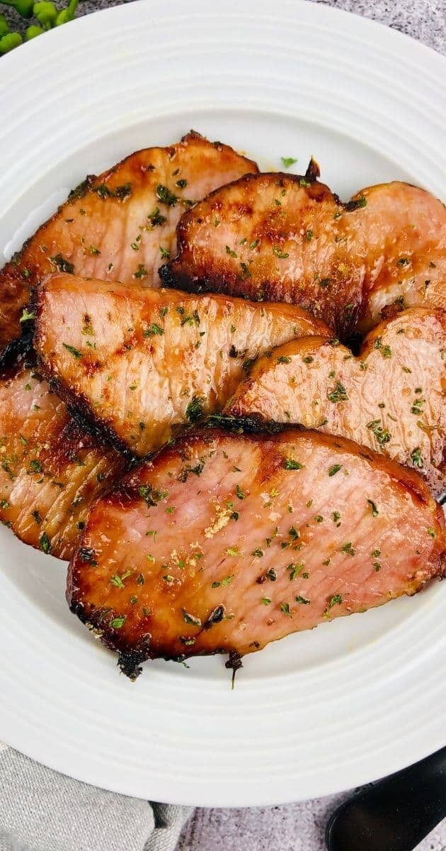 close up vertical image of air fryer ham on a white plate