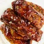 Cooked and sauced pork ribs on a white plate.