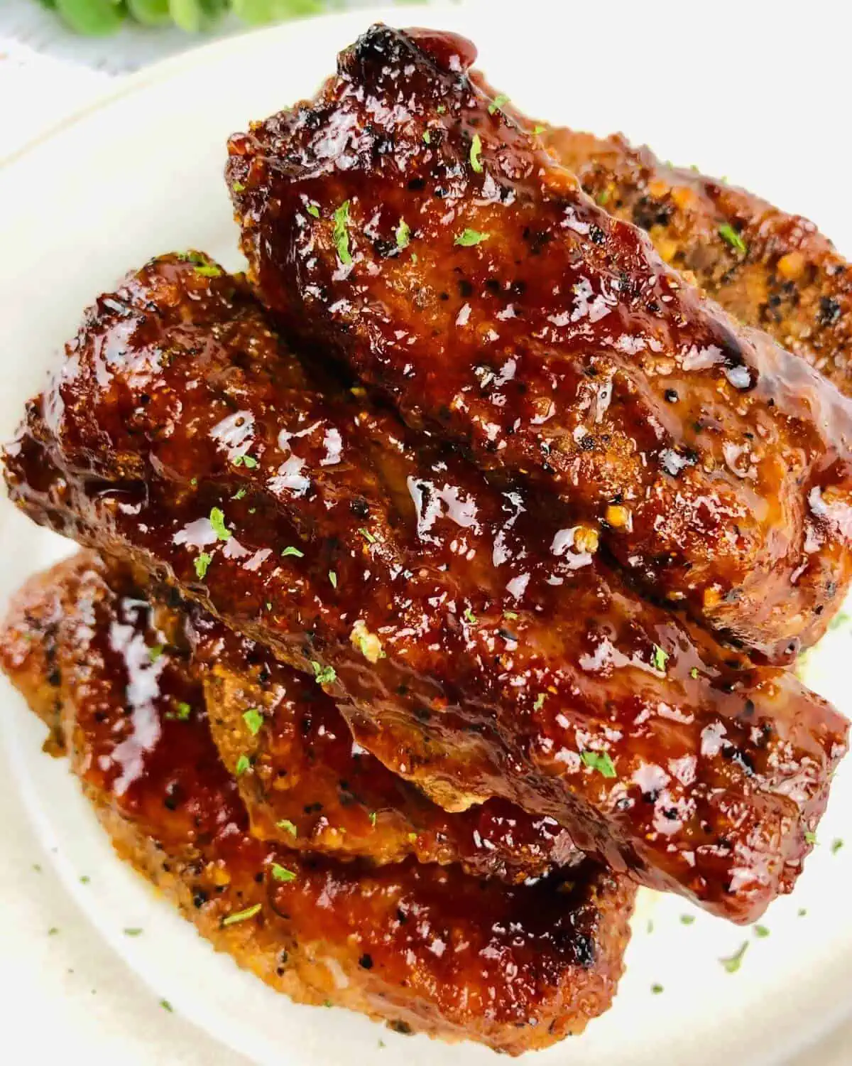 Cooked and sauced pork ribs on a white plate.