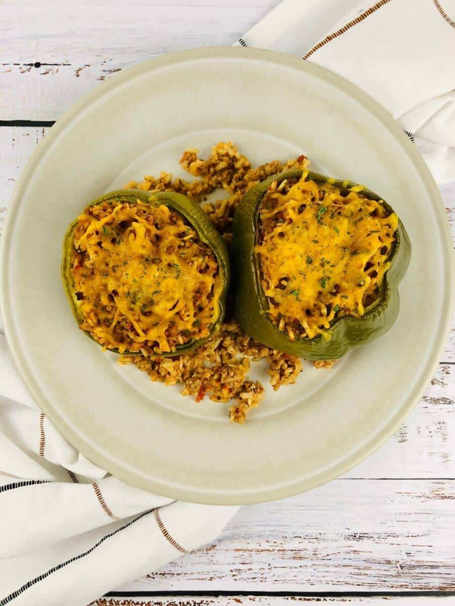top view of two air fryer stuffed peppers on a white plate.