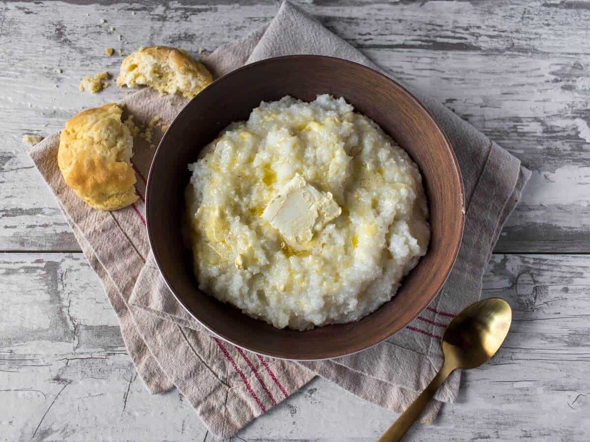 image of grits in a wooden bowl with butter for the post titled "are grits gluten free?"