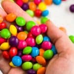 Hand holding a bunch of Skittles candies for the article titled: Are Skittles Gluten Free?