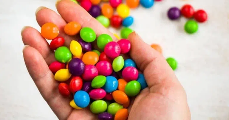 Hand holding a bunch of Skittles candies for the article titled: Are Skittles Gluten Free?