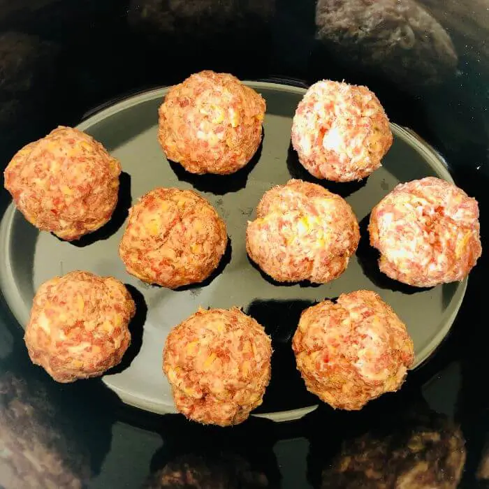 raw gluten free sausage balls in the bottom of a slow cooker.