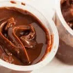 Two chocolate Hunts Snack Pack pudding cups open on a a table.