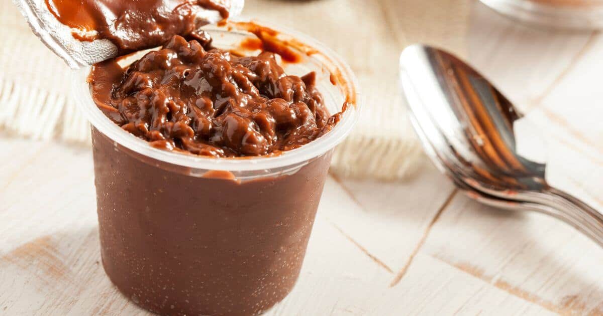 Container of chocolate Hunt's Snack Pack pudding next ot a spoon.