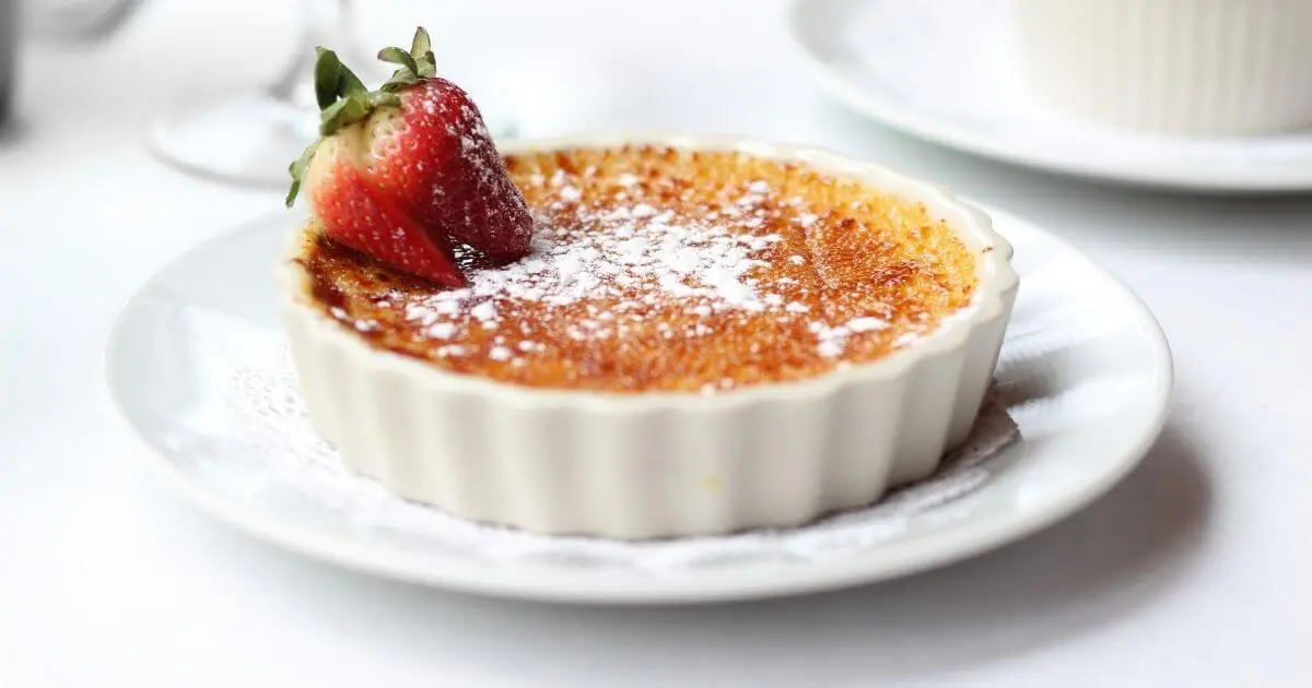 Creme brulee in a ramekin on a white plate.