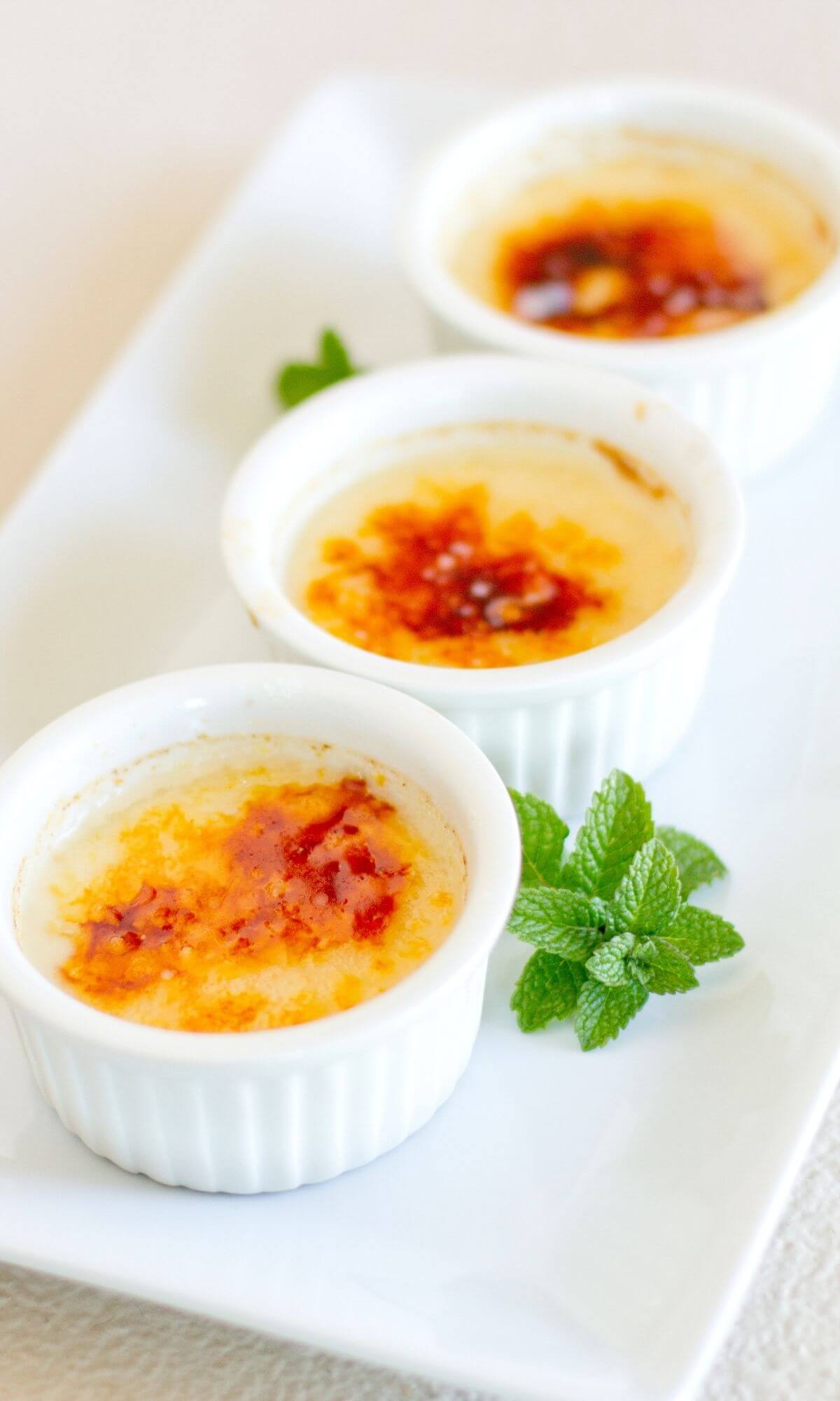 3 ramekins with creme brulee on a white plate.