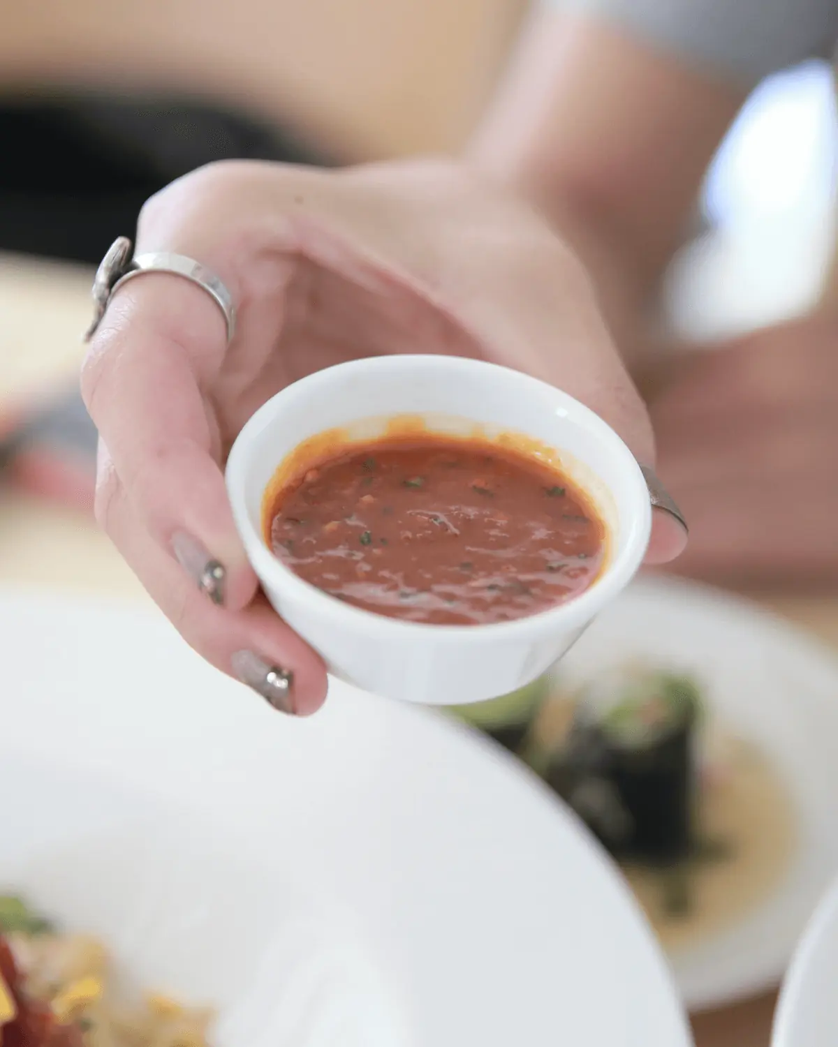 A hand holding a small bowl filled with Gochujang.