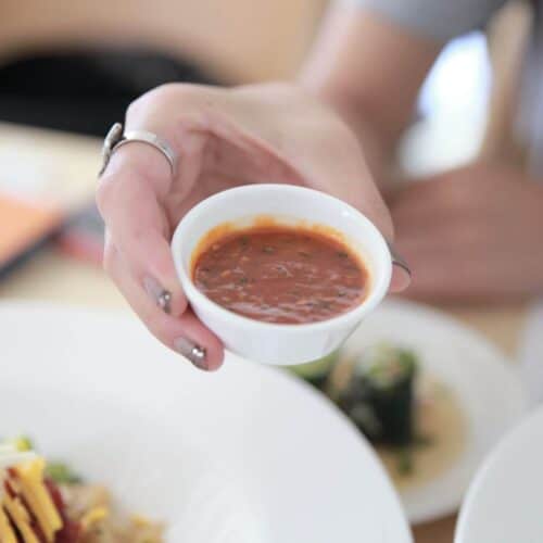 A hand holding a small bowl filled with Gochujang.
