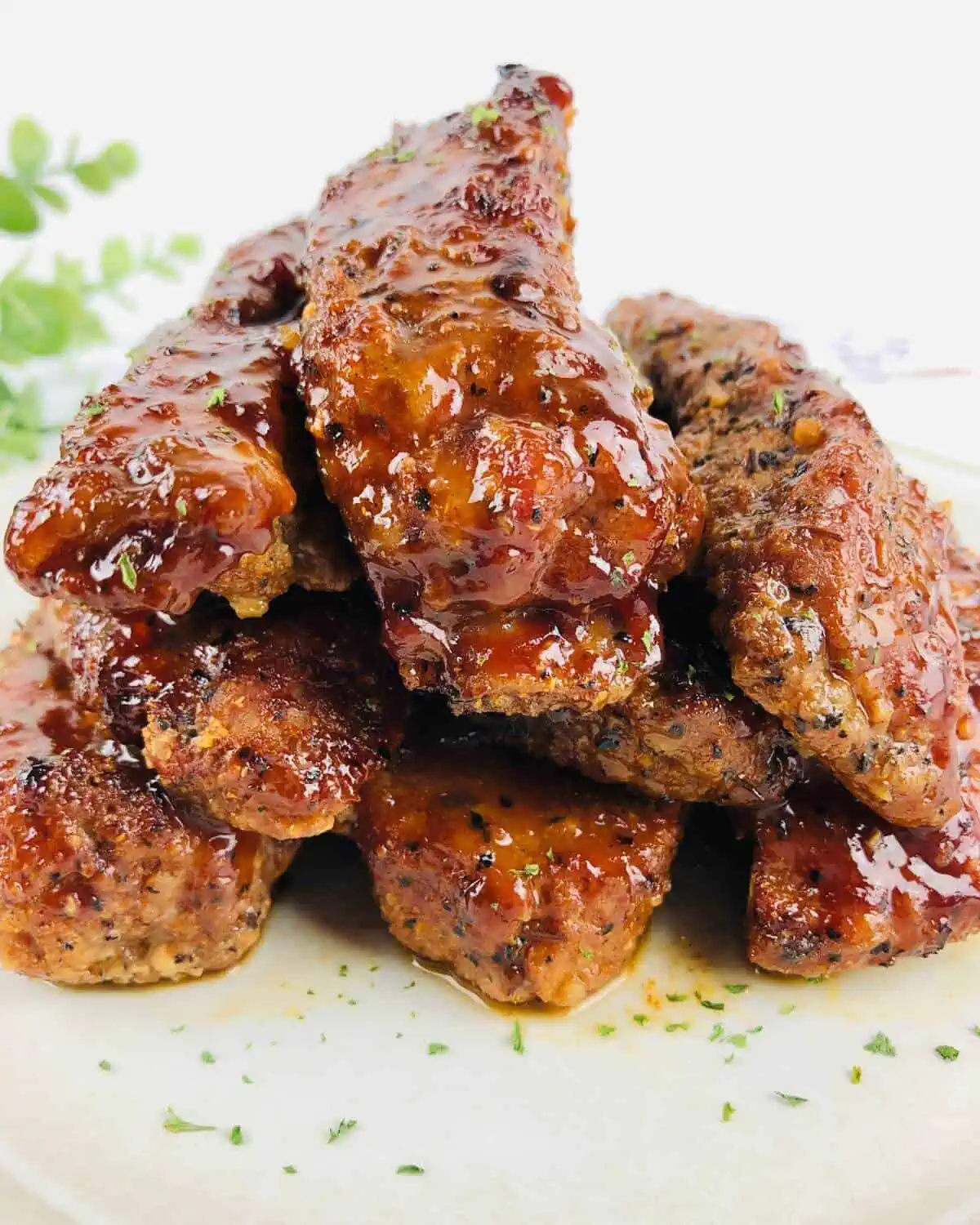 Cooked and sauced pork ribs on a white plate.