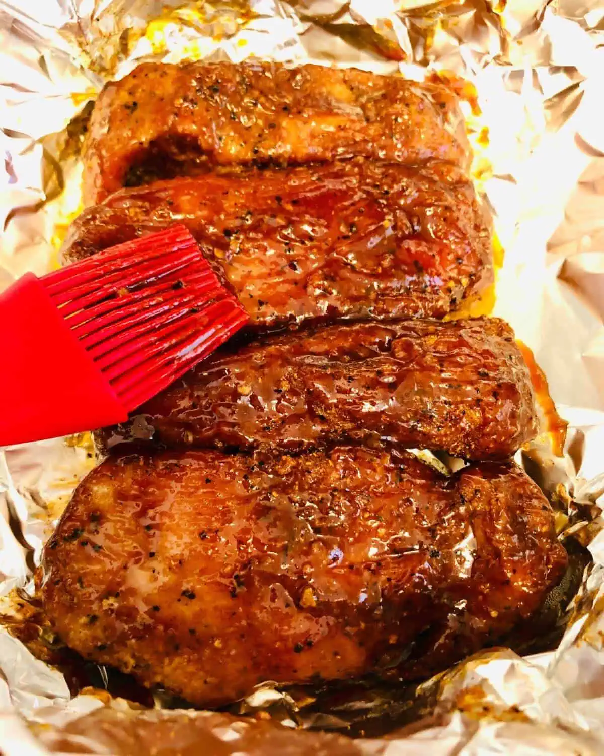 Pork ribs being brushed with bbq sauce.