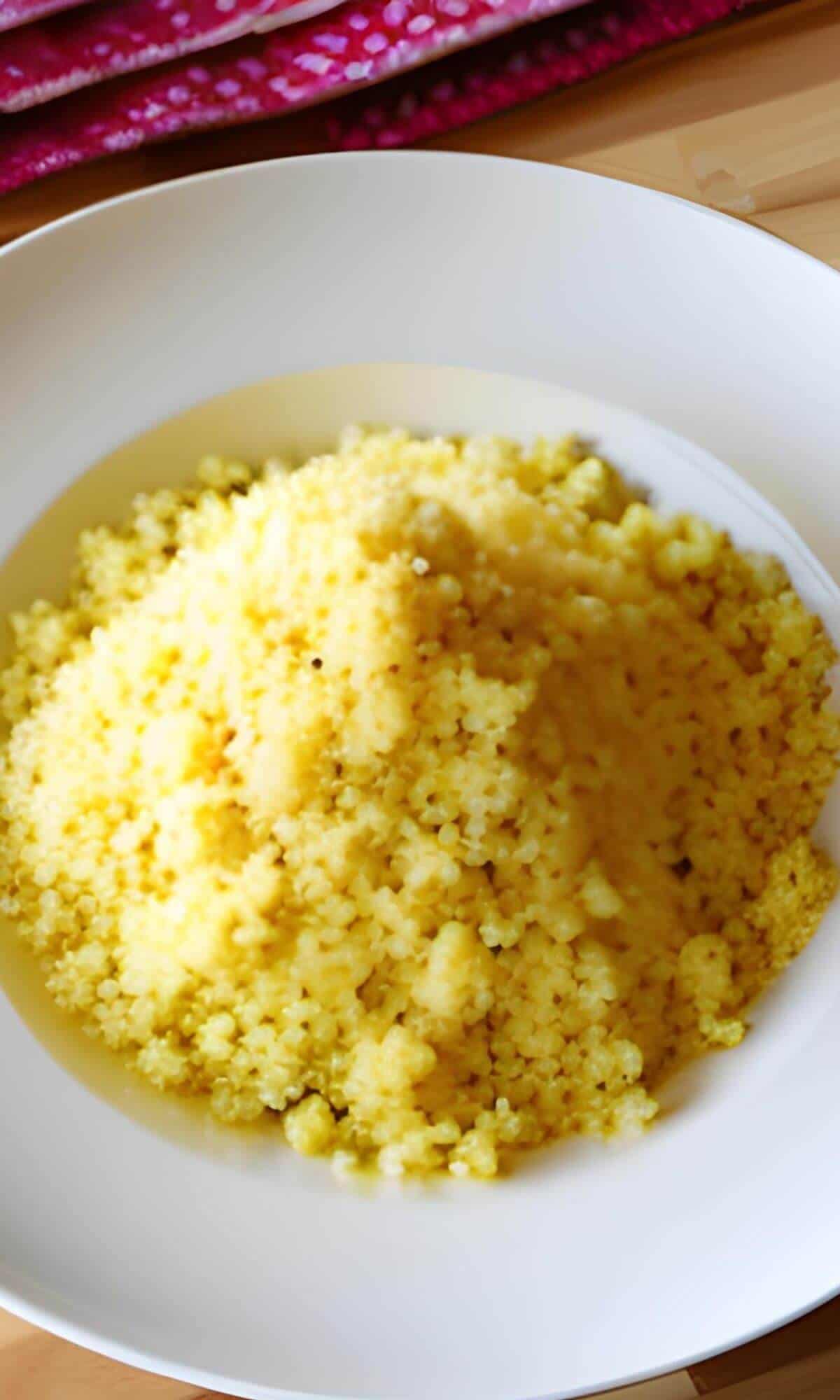 A white plate full of yellow couscous.