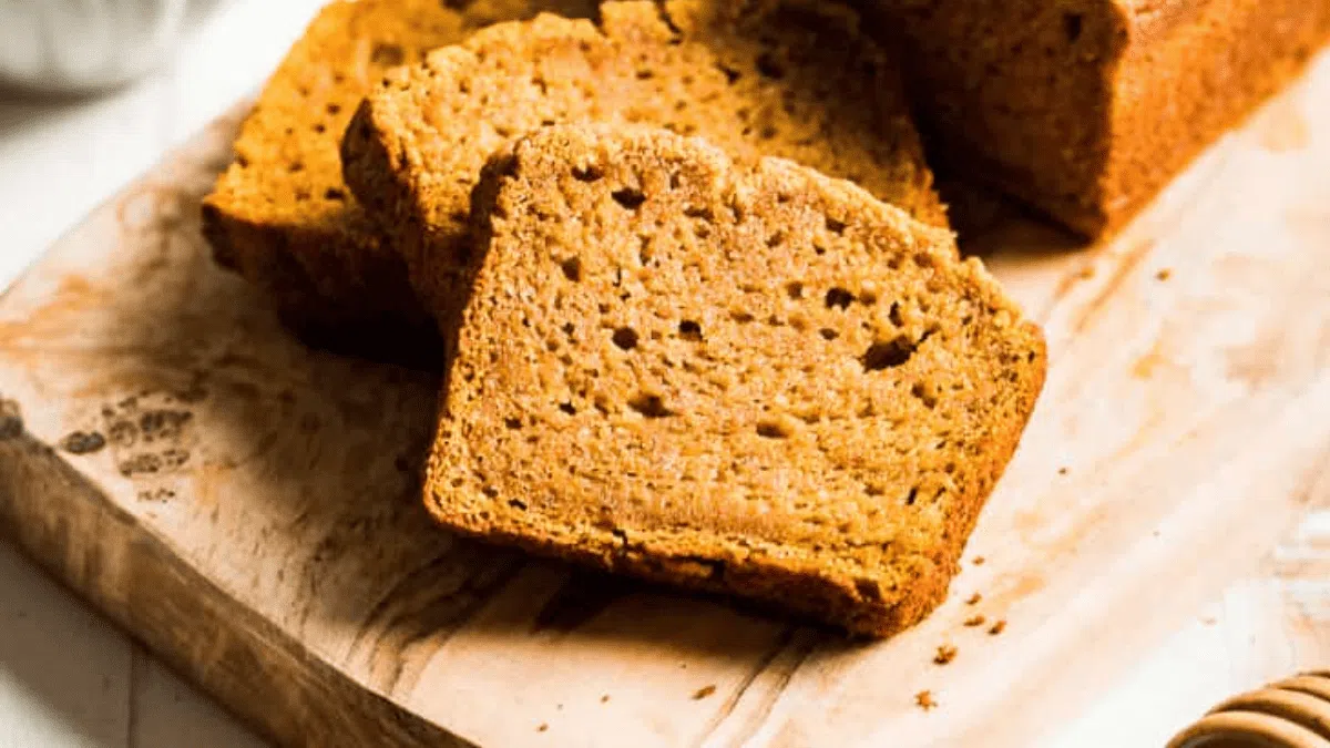 A pumpkin bread sliced on a bread board.