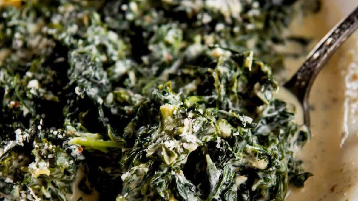 A dish of creamed kale with a serving spoon.