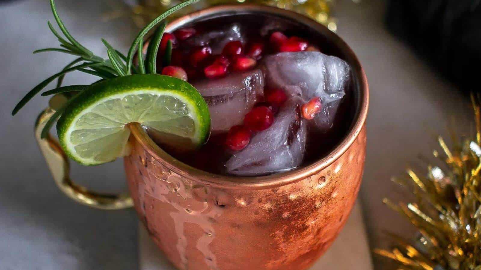 A pomegranate virgin moscow mule in a copper mug with lime wedge, ice and cranberries.