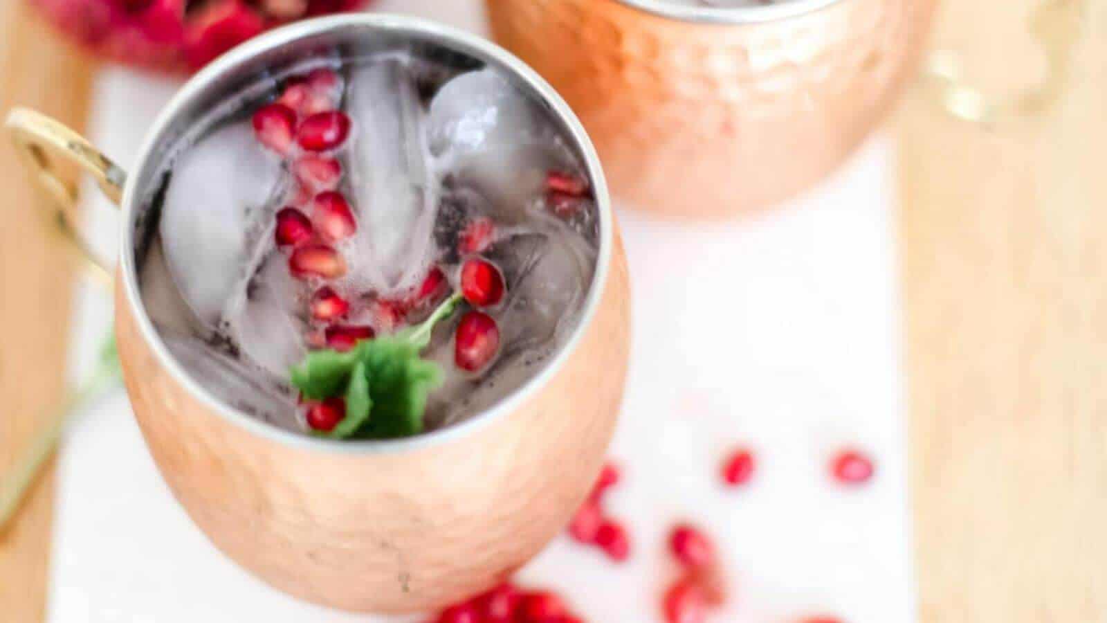 Pomegranate mocktail in a copper mug with cranberries.