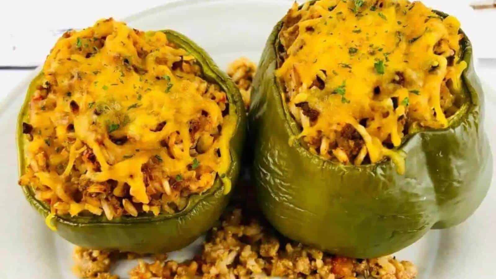 Two stuffed green peppers on a plate.