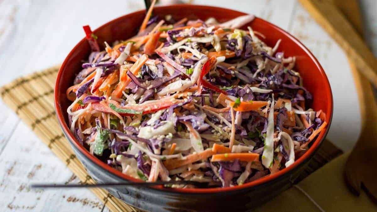 Asian cabbage slaw with sesame mayo in a red bowl.