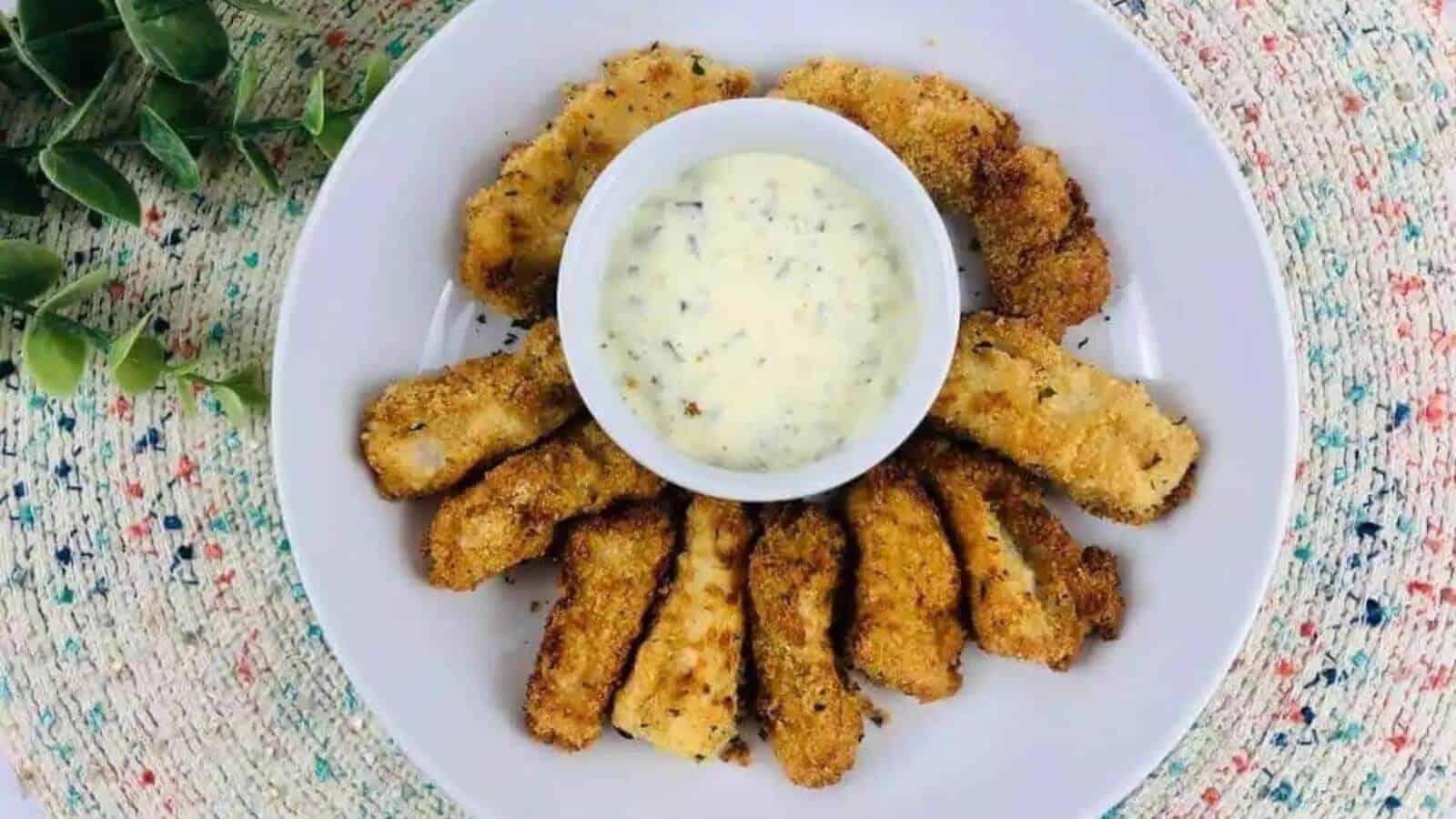 Gluten free fish sticks on a plate with dipping sauce.