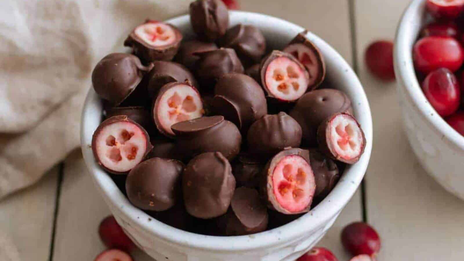 Chocolate covered cranberries in a white bowl.