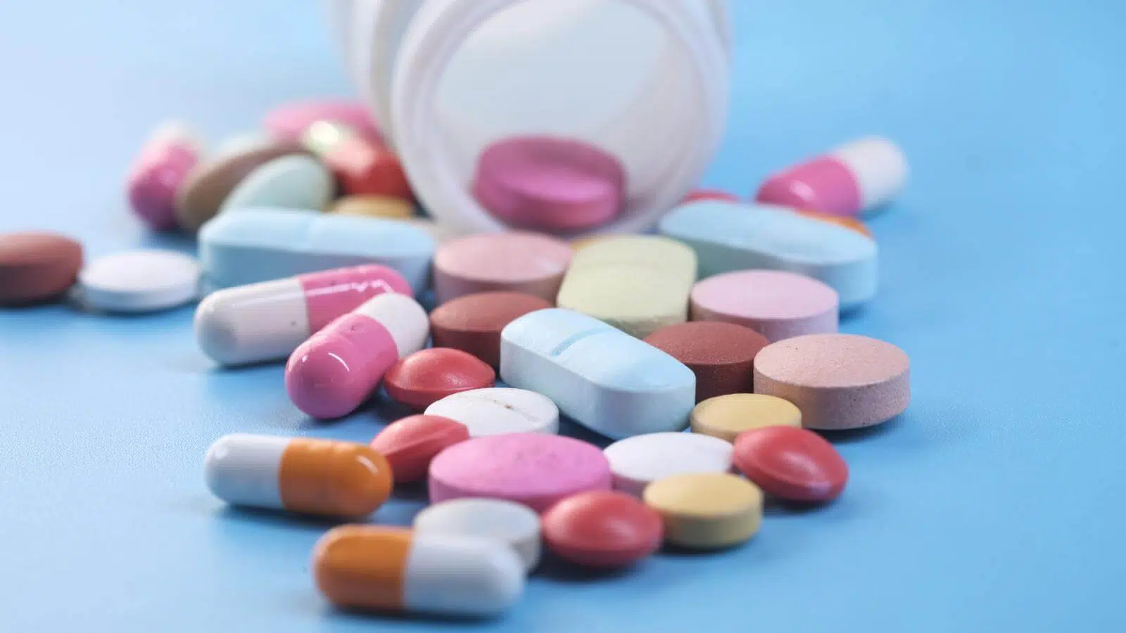 A bottle spilling out multicolored pills.