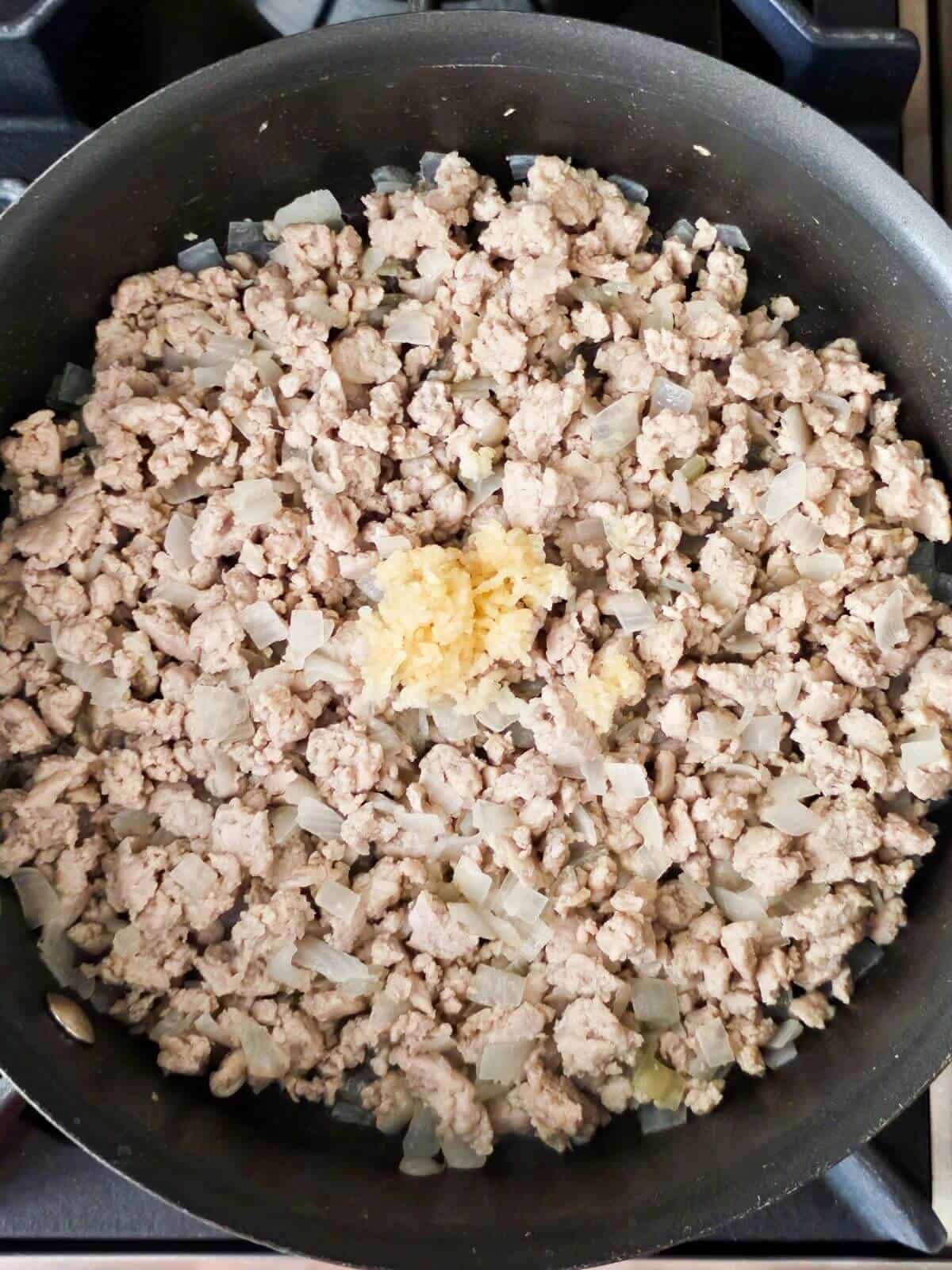 Browned ground chicken and minced garlic in a skillet.