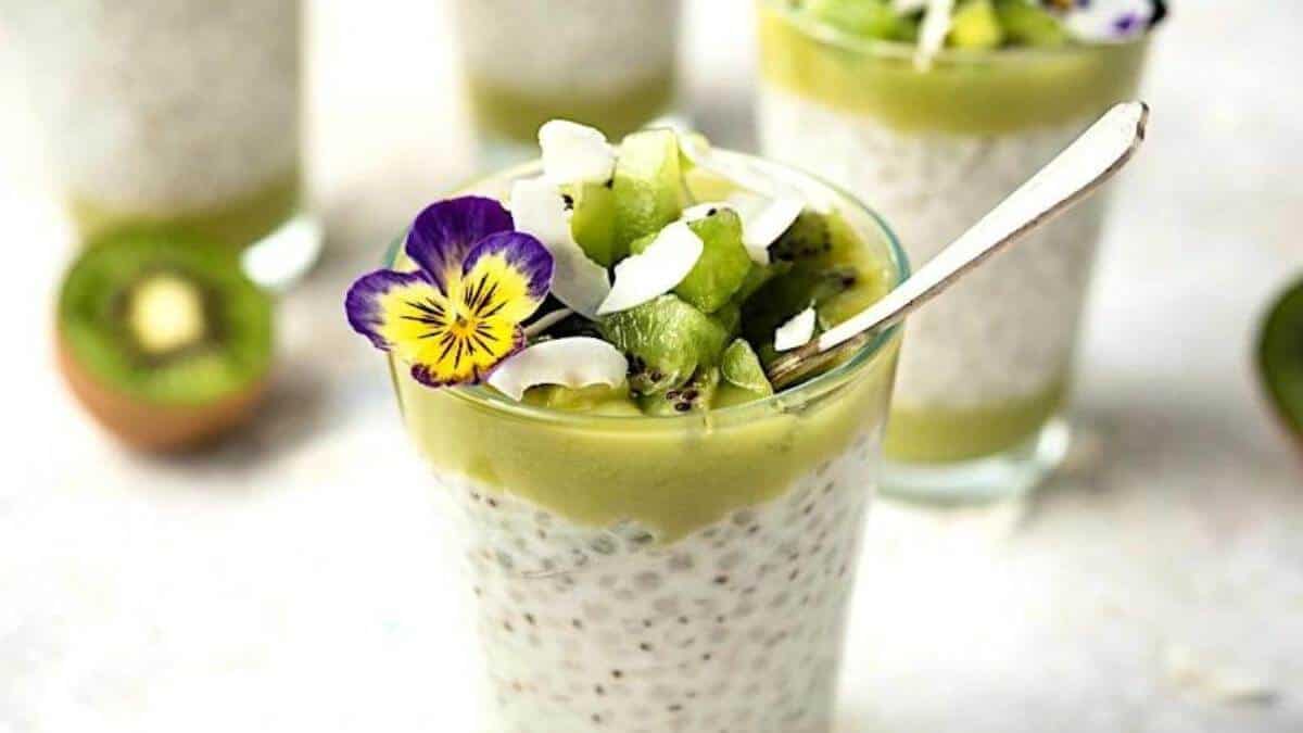 Kiwi chia seed pudding in a glass topped with flowers.