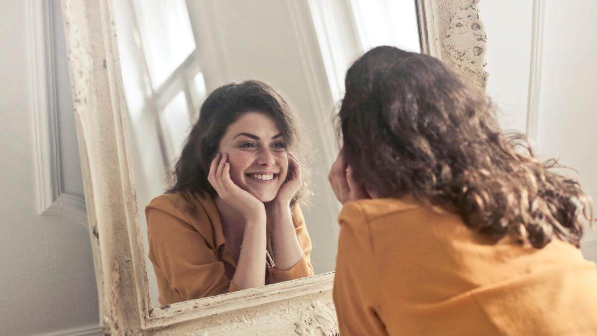 A woman looking in a mirror and smiling.