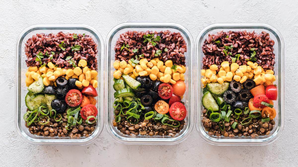 Three glass containers filled with meal-prepped food.