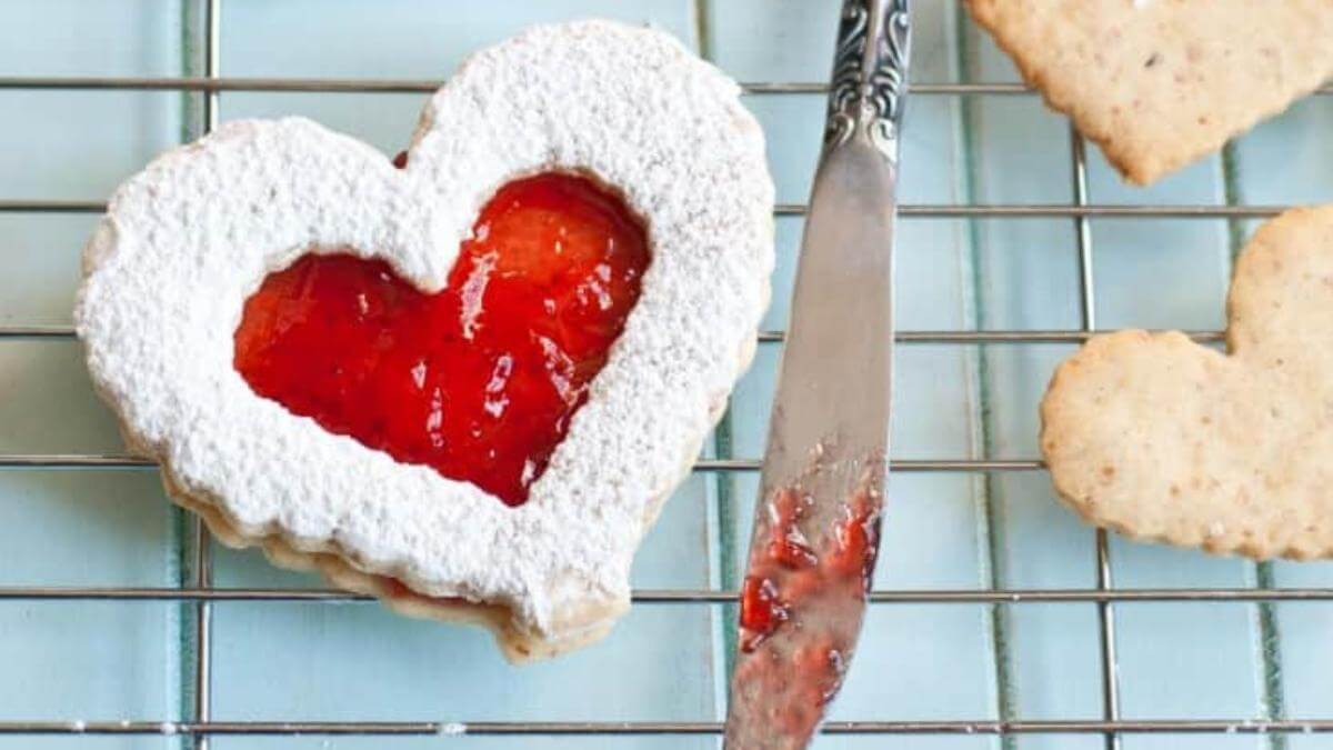Heart shaped cookie with heart shaped red jam in the middle.