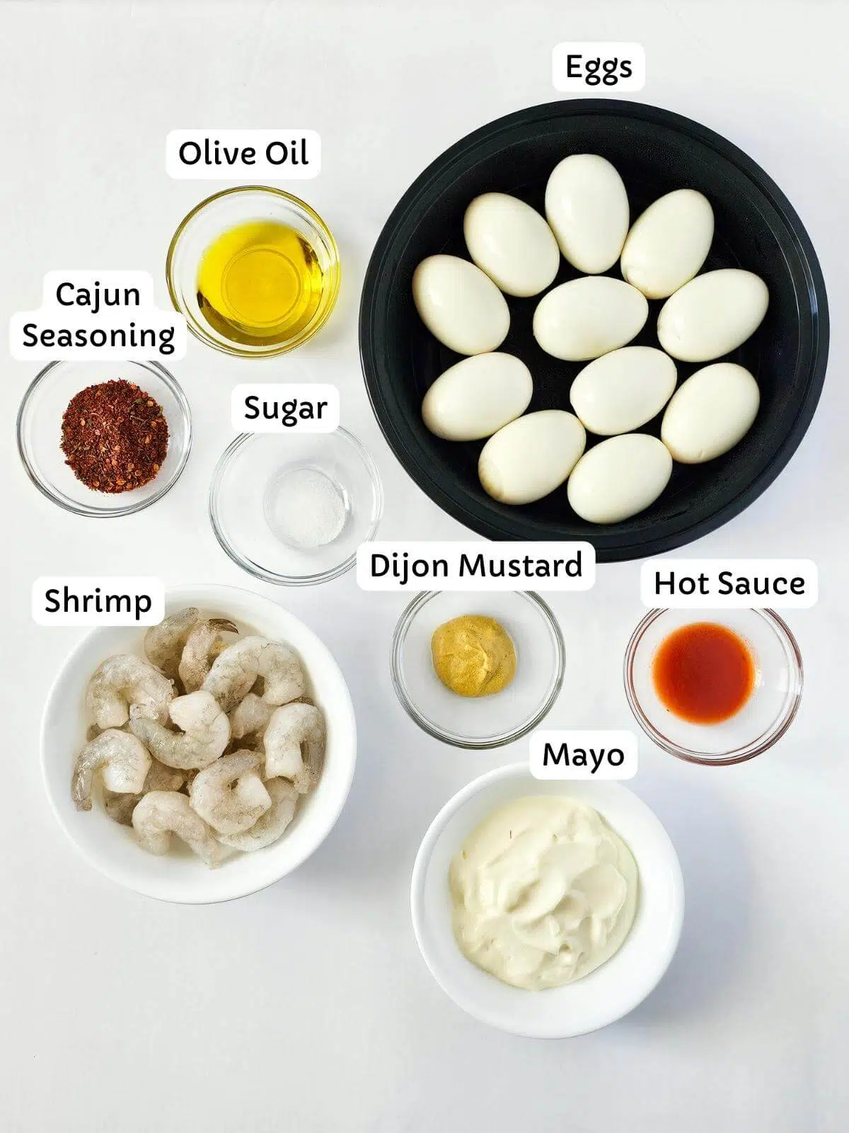 Ingredients for making Cajun devlied eggs in small bowls.