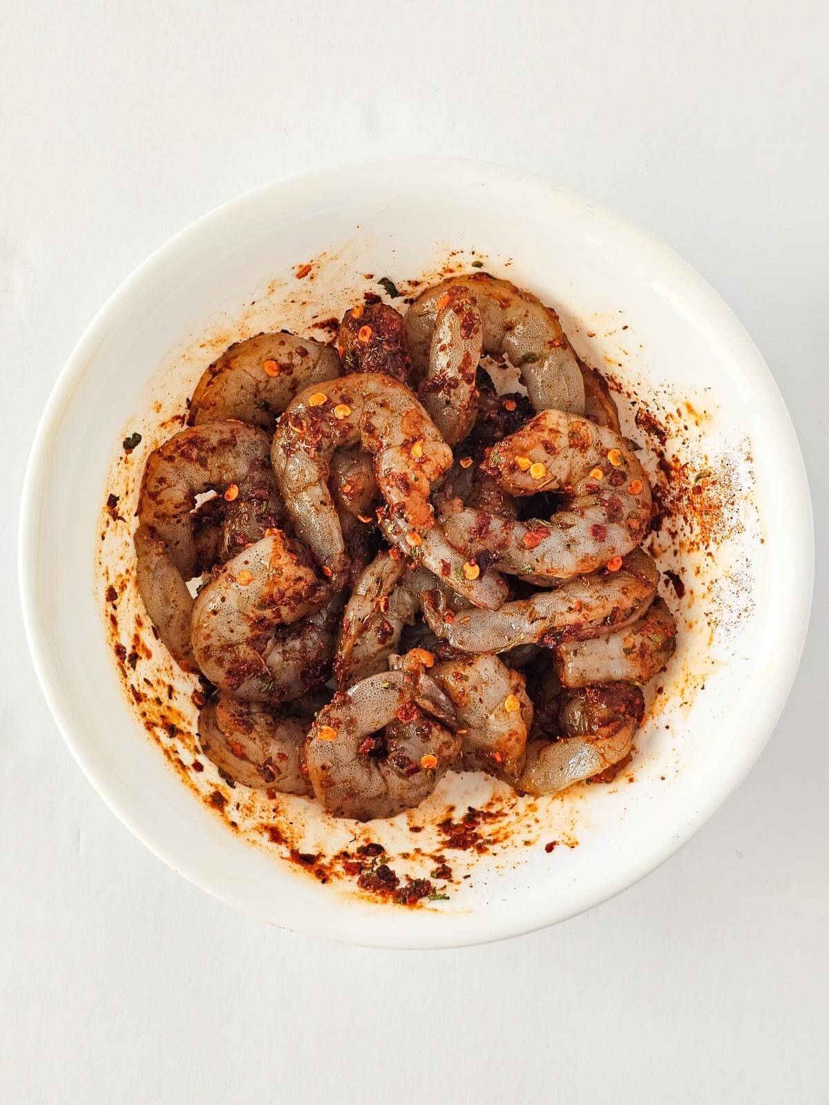 Raw seasoned shrimp in a bowl.