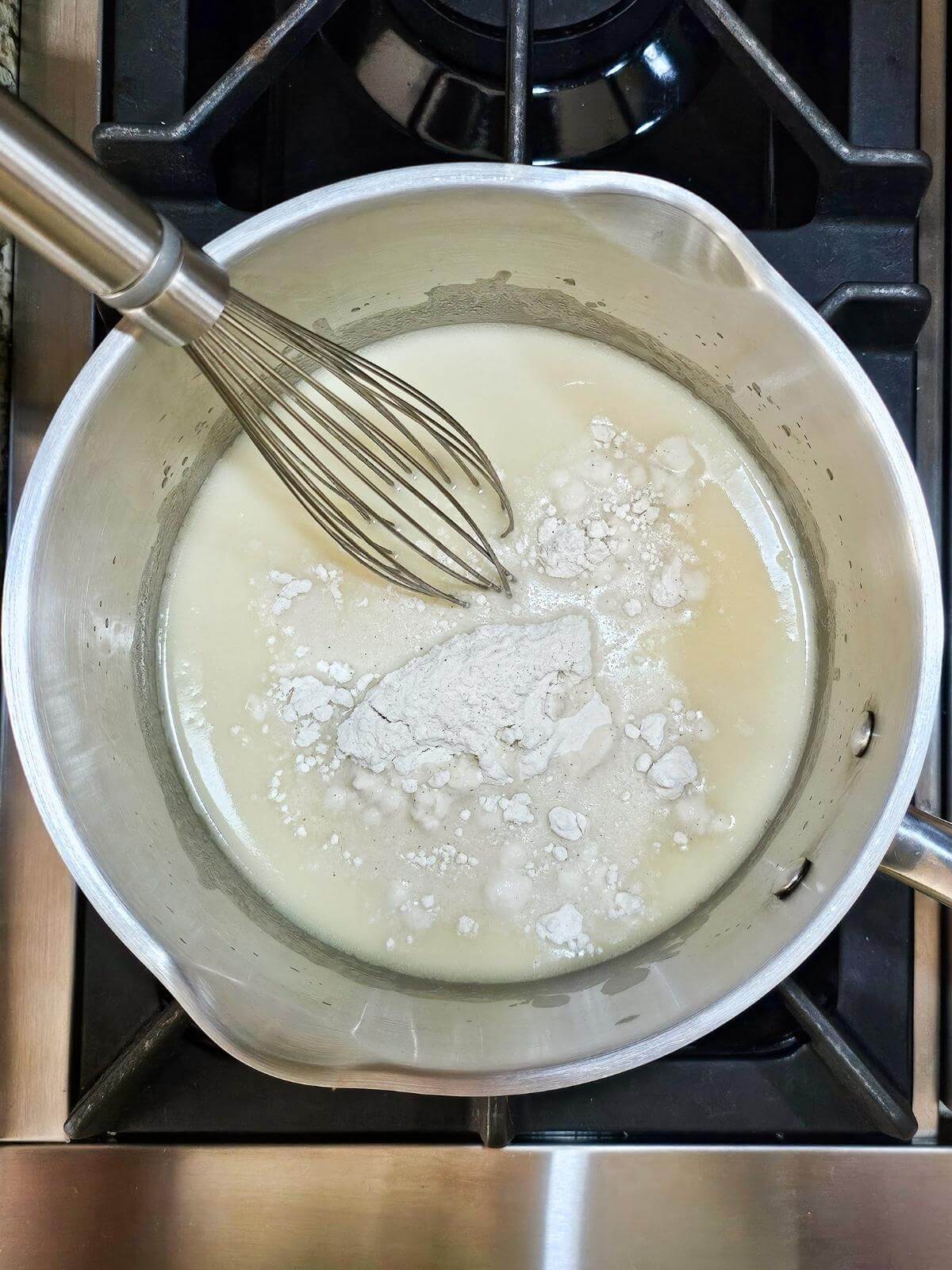 Flour, milk and a whisk in a pot.