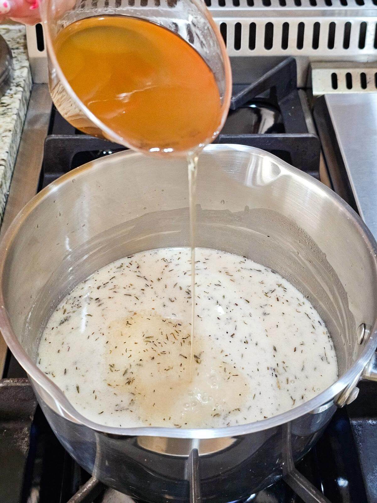Broth being poured into a pot of seasoned milk mixture.