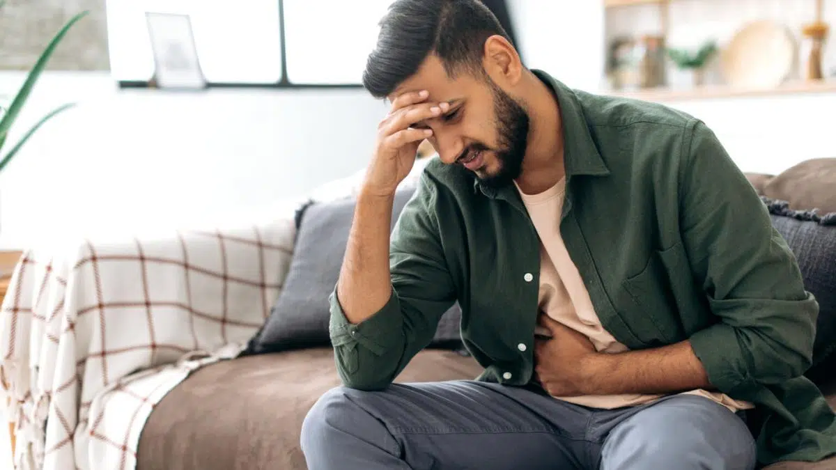 A man holding his head and stomach in pain.