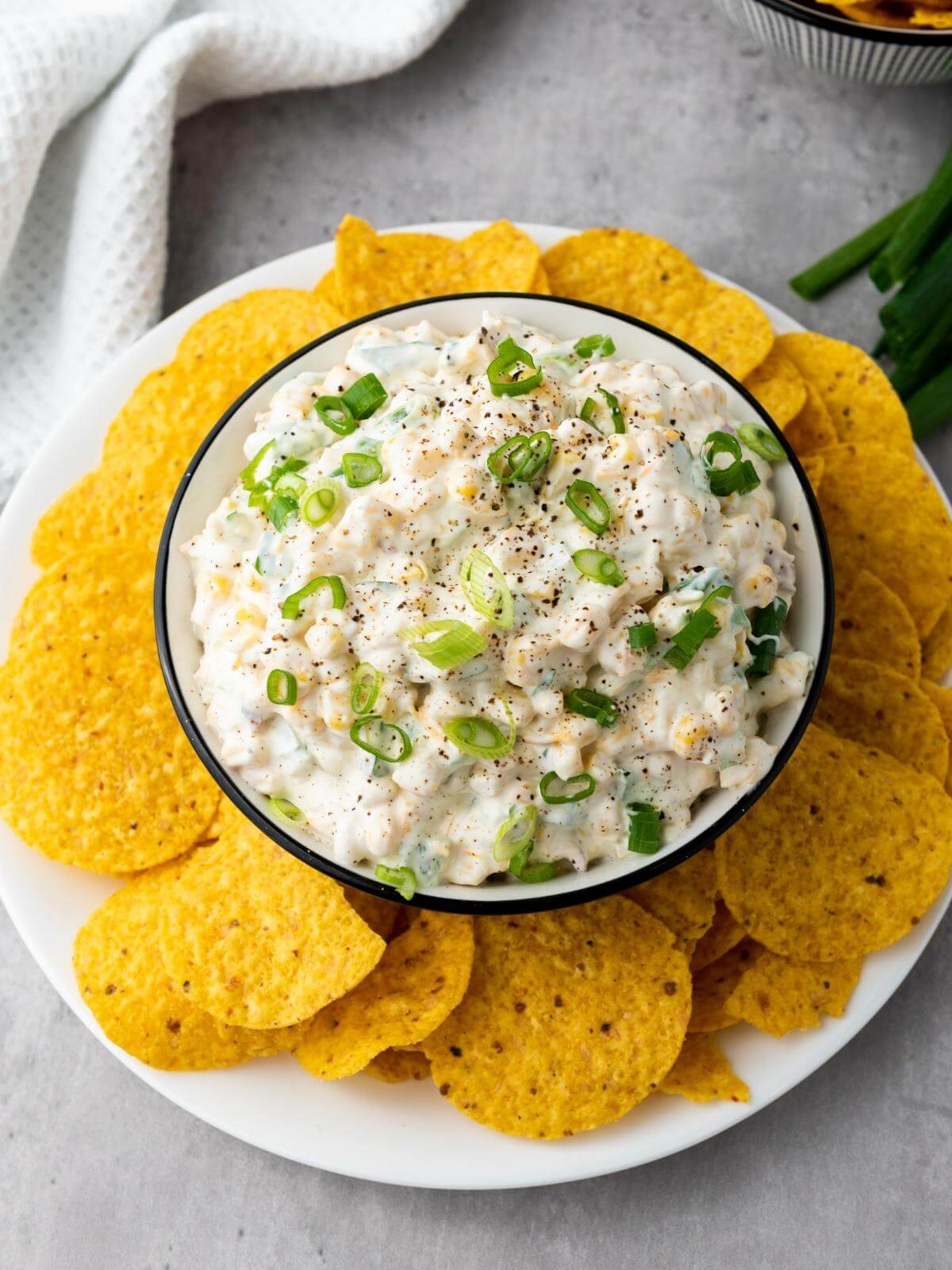 Creamy corn dip in a bowl with tortilla chips.