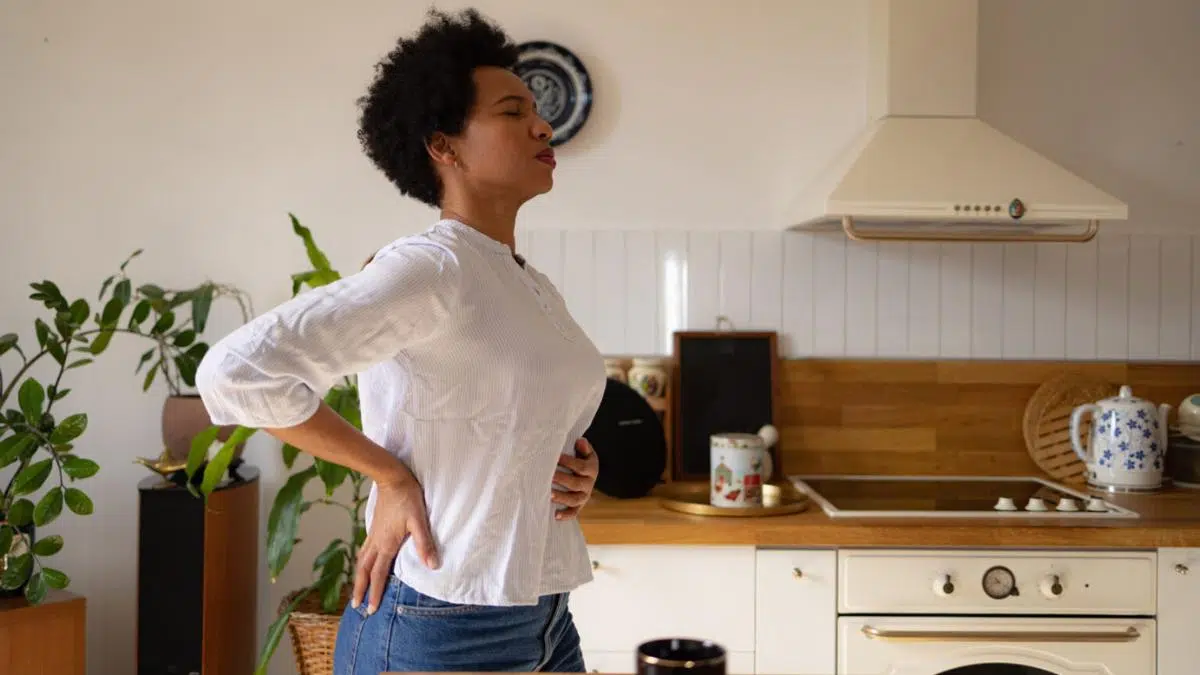 A woman holding her back in discomfort.