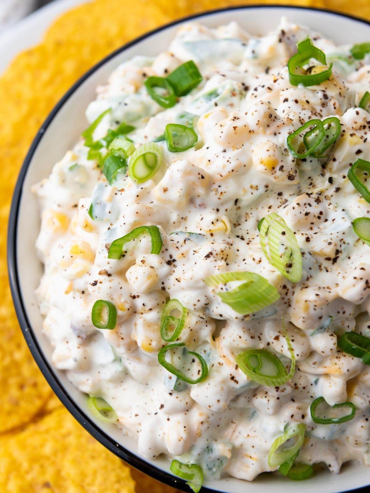 Creamy corn dip in a bowl with tortilla chips.