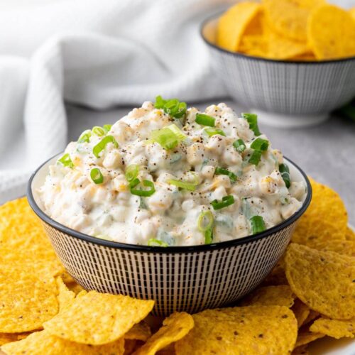 A bowl of creamy corn dip with tortilla chips.