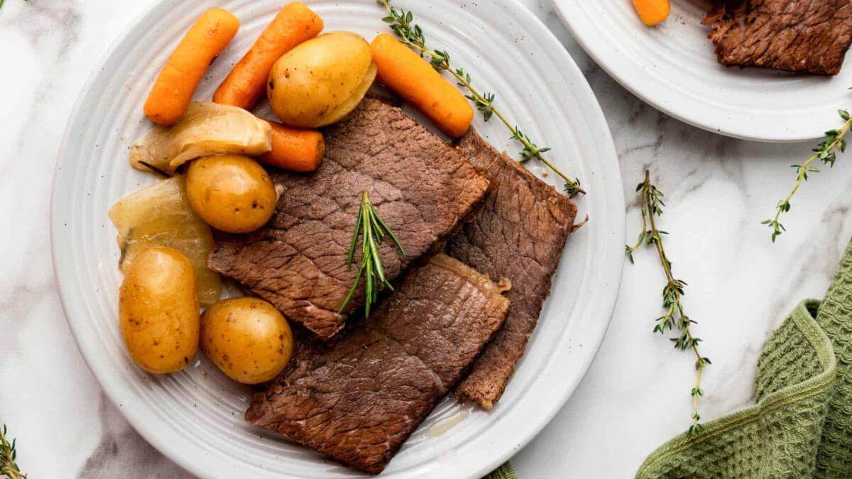 Rump roast with carrots and potatoes on a plate.