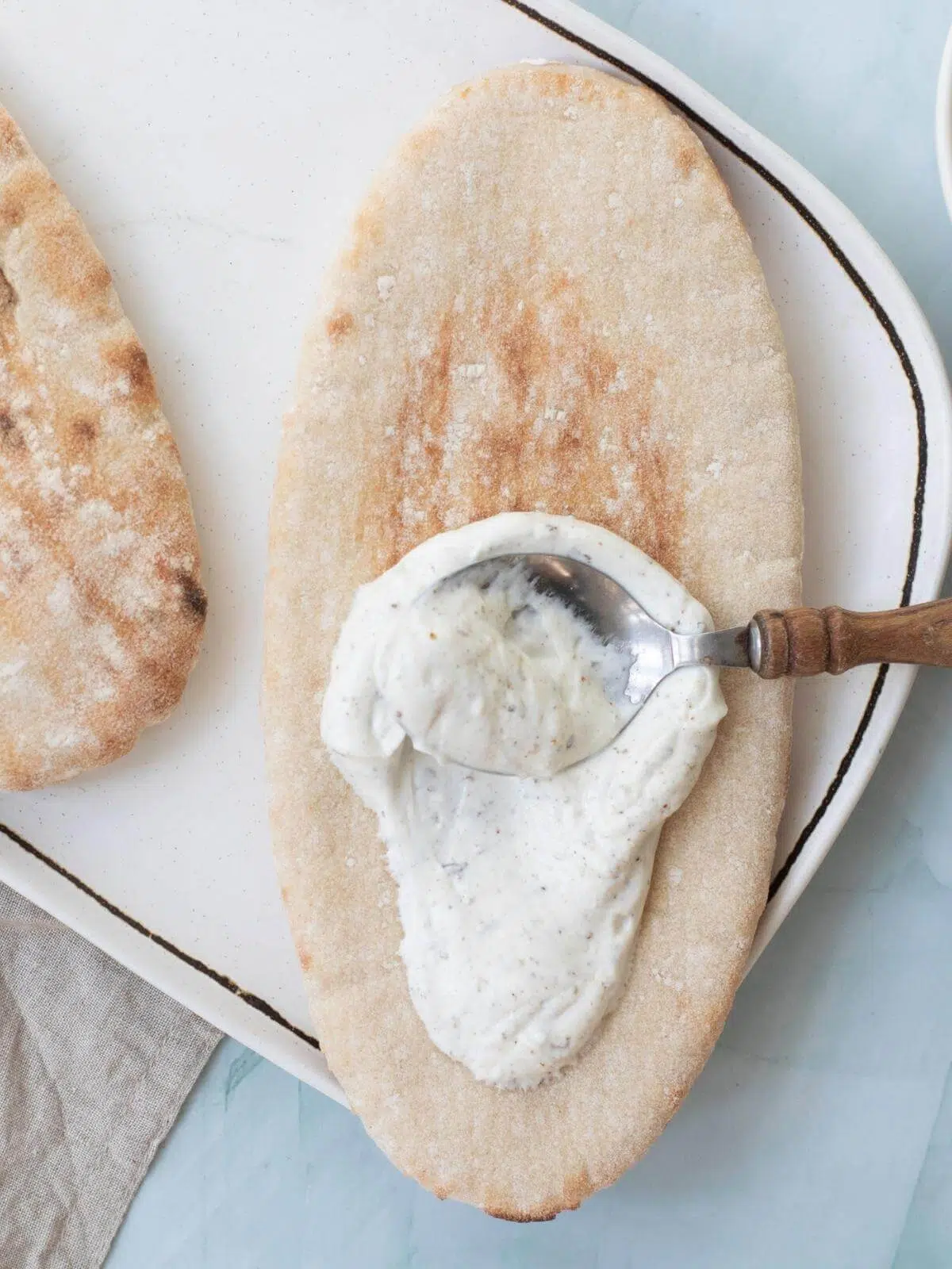 Yogurt being spread on a pita bread.