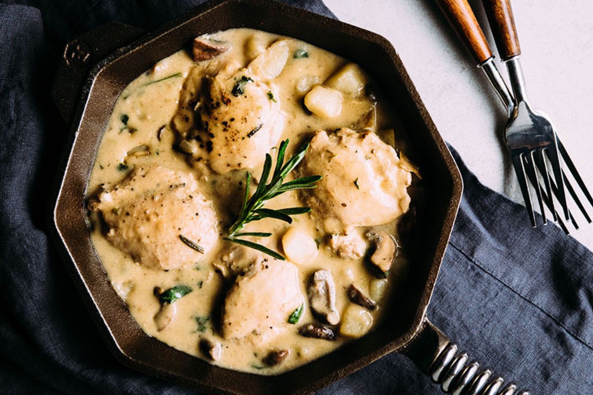 Chicken and potatoes in a skillet.