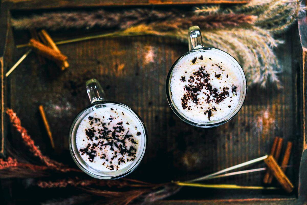 A white custard drink in two glass mugs.