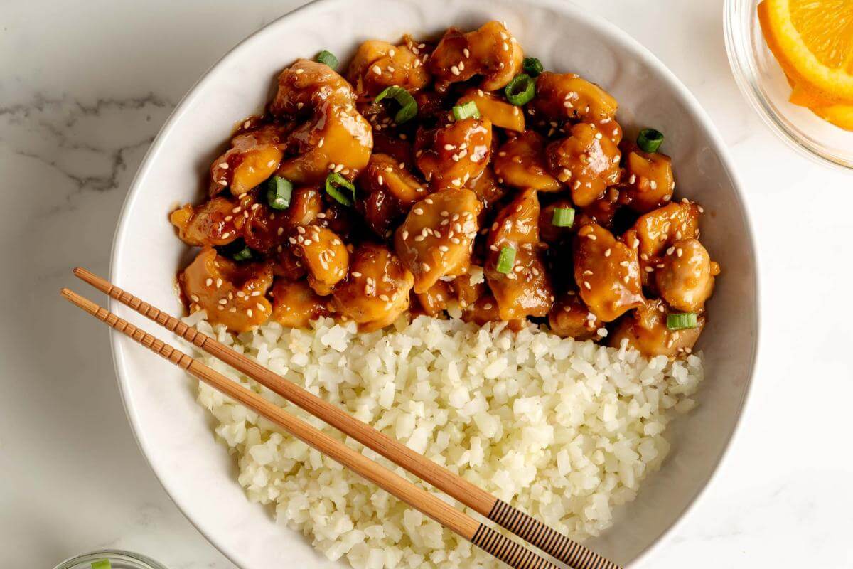 A bowl of orange chicken and rice.