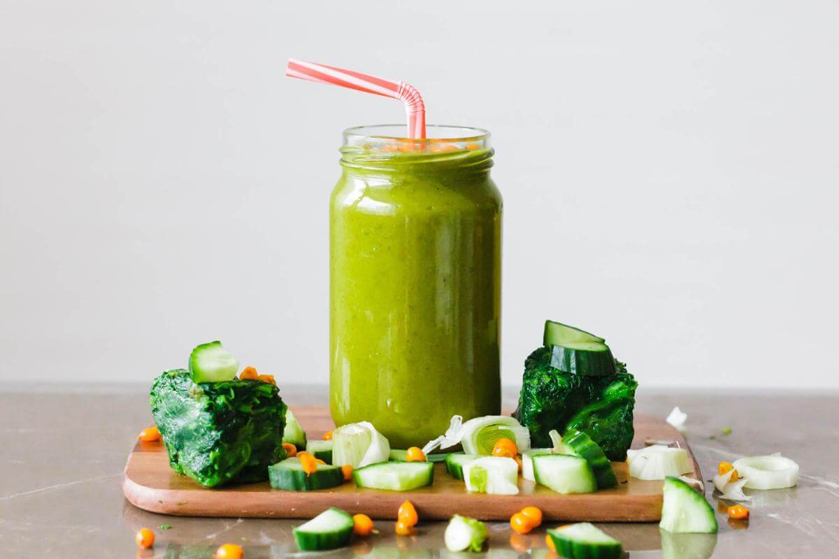 A green smoothie in a glass with a straw.