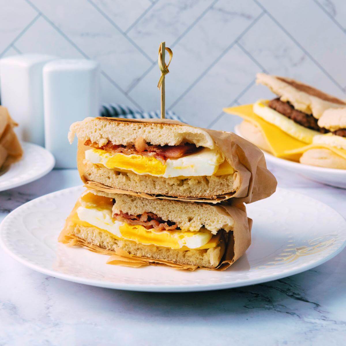 A breakfast sandwich cut in half on a plate.